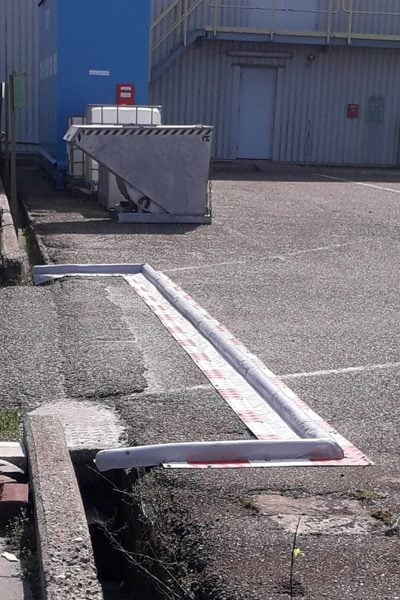 Barrière anti-déversement à marquage rouge-blanc à l'entrée des camions d'un parc chimique, franchissable