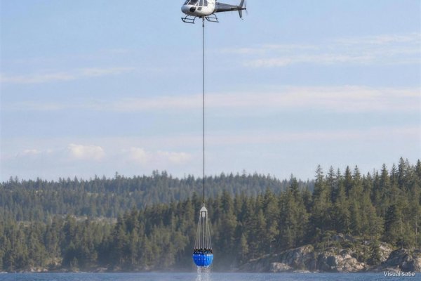 Helicopter scooping water with the bucket on a short line