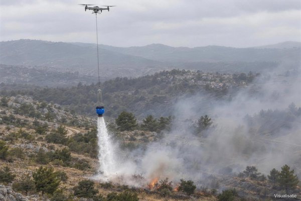 Firefighting drone releasing the full bucket over the fire front