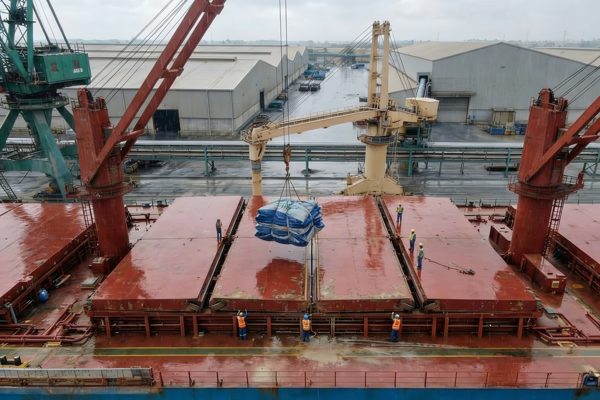 The folded rain cover being hoisted onto the closed hatch by crane