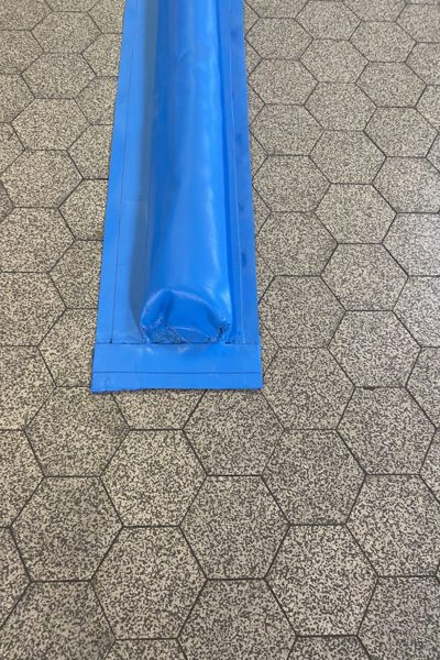 Seuil de rétention de liquides collé sur un sol carrelé dans un hall de production
