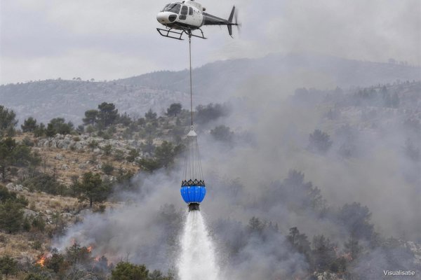 Helicopter releasing the bucket over a forest fire